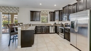 A modern kitchen with dark cabinets, stainless steel appliances, and a central island. - Imagine You and Your Family Renting This 5 Star Villa on Champions Gate Resort, Orlando Villa 3611 (Davenport)