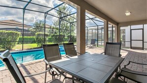 A covered outdoor area with a pool, chairs, and a table. - Imagine You and Your Family Renting This 5 Star Villa on Champions Gate Resort, Orlando Villa 3611 (Davenport)