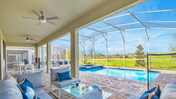 A covered outdoor area with a pool, seating, and a view of the landscape.