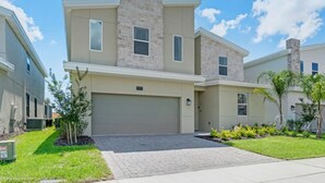 A two-story townhouse with a stone facade, a garage, and a well-maintained lawn. - You and Your Family Will Love This Luxury Mansion on Champions Gate Resort, Orlando Mansion 3726 (Davenport)