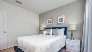 A neatly arranged bedroom with a bed, bedside tables, and two framed pictures on the wall.