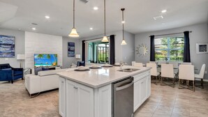 A modern kitchen with a central island, white cabinetry, and pendant lighting. - Luxury 5 Star Villa on Solterra Resort, Orlando Villa 3692 (Davenport)