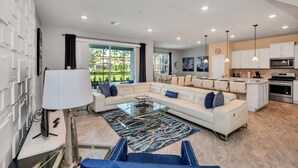 A modern living room with a sectional sofa, a glass coffee table, and a view of the outdoors. - Luxury 5 Star Villa on Solterra Resort, Orlando Villa 3692 (Davenport)