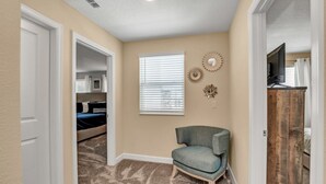 A bedroom with a bed, a chair, a TV, and a wooden cabinet. - Rent the Perfect Luxury Villa on Champions Gate Resort, Orlando Villa 3707 (Davenport)