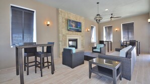 A spacious living area with a fireplace, comfortable seating, and a flat-screen TV mounted on a stone wall. - The Secret to Enjoying Your Luxury Townhome on Windsor at Westside Resort, Orlando Townhome 3722 (Kissimmee)