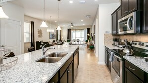 A modern kitchen with granite countertops, stainless steel appliances, and a dining area with a view.