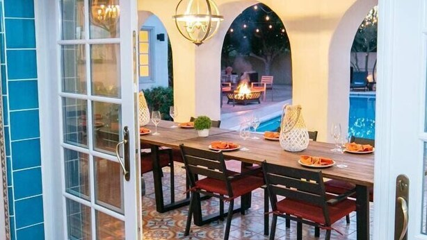 An outdoor dining area with a pool view, a fire pit, and a patterned floor. - Royal Palms (Phoenix)
