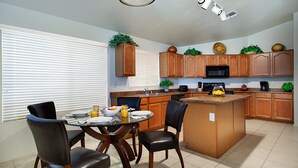 A modern kitchen with wooden cabinets, a central island, and a dining area with chairs. - Near Great Shopping & Dining! Pool Table & Games! (Glendale)