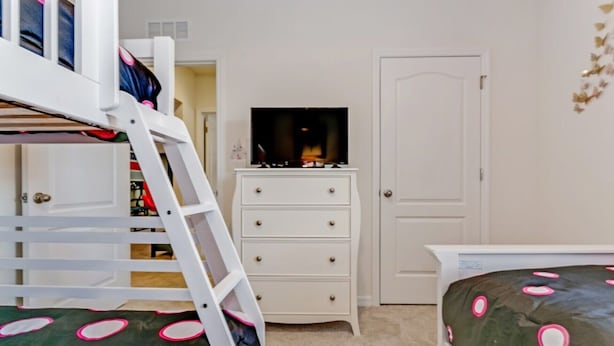 A bedroom with bunk beds, a dresser, a television, and a door. - Picture Renting Your Own Luxury Villa on the Exclusive Solterra Resort, Close to Disney, Orlando Villa 3690 (Davenport)