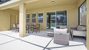 A covered patio area with outdoor furniture, a sliding glass door leading to a pool, and a door to the left. - Picture Renting Your Own Luxury Villa on the Exclusive Solterra Resort, Close to Disney, Orlando Villa 3690 (Davenport)