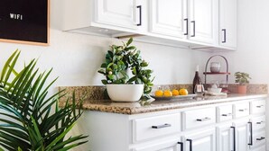 A kitchen with white cabinets, a granite countertop, a potted plant, and a bowl of lemons. - Perfect 4 Bdrm Home With Pool and Game Room! (Phoenix)