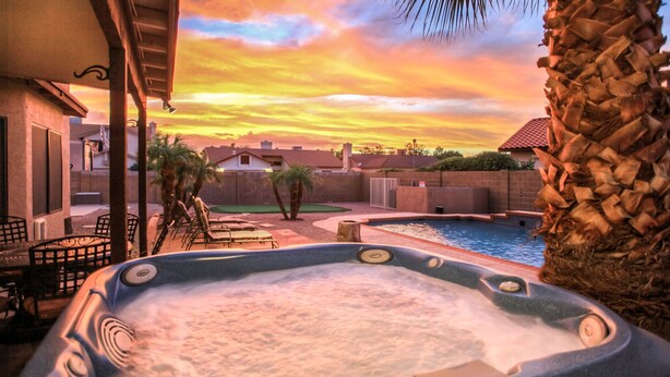 A hot tub with a pool, palm trees, and a sunset view. - Backyard Playground! Golf Sport Court & Hot Tub! (Glendale)
