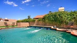 A swimming pool with clear blue water, surrounded by a tiled deck and two lounge chairs. - Backyard Playground! Golf Sport Court & Hot Tub! (Glendale)