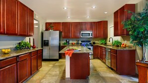 A modern kitchen with wooden cabinets, stainless steel appliances, and a central island. - Backyard Playground! Golf Sport Court & Hot Tub! (Glendale)