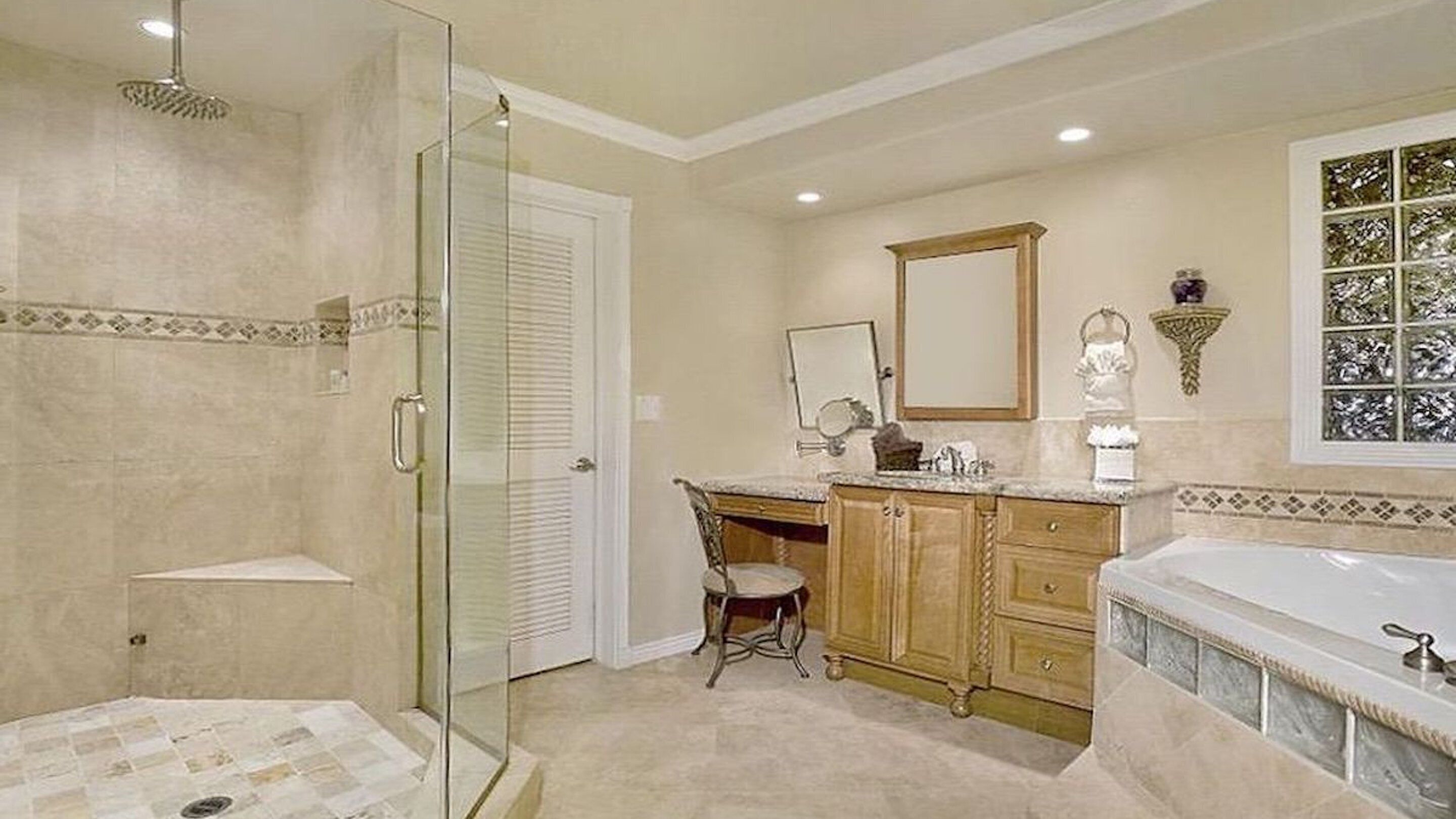 A bathroom with a glass-enclosed shower, a vanity with a mirror, and a bathtub.