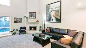 Un salon avec une cheminée, un grand tableau, un canapé et une table basse.