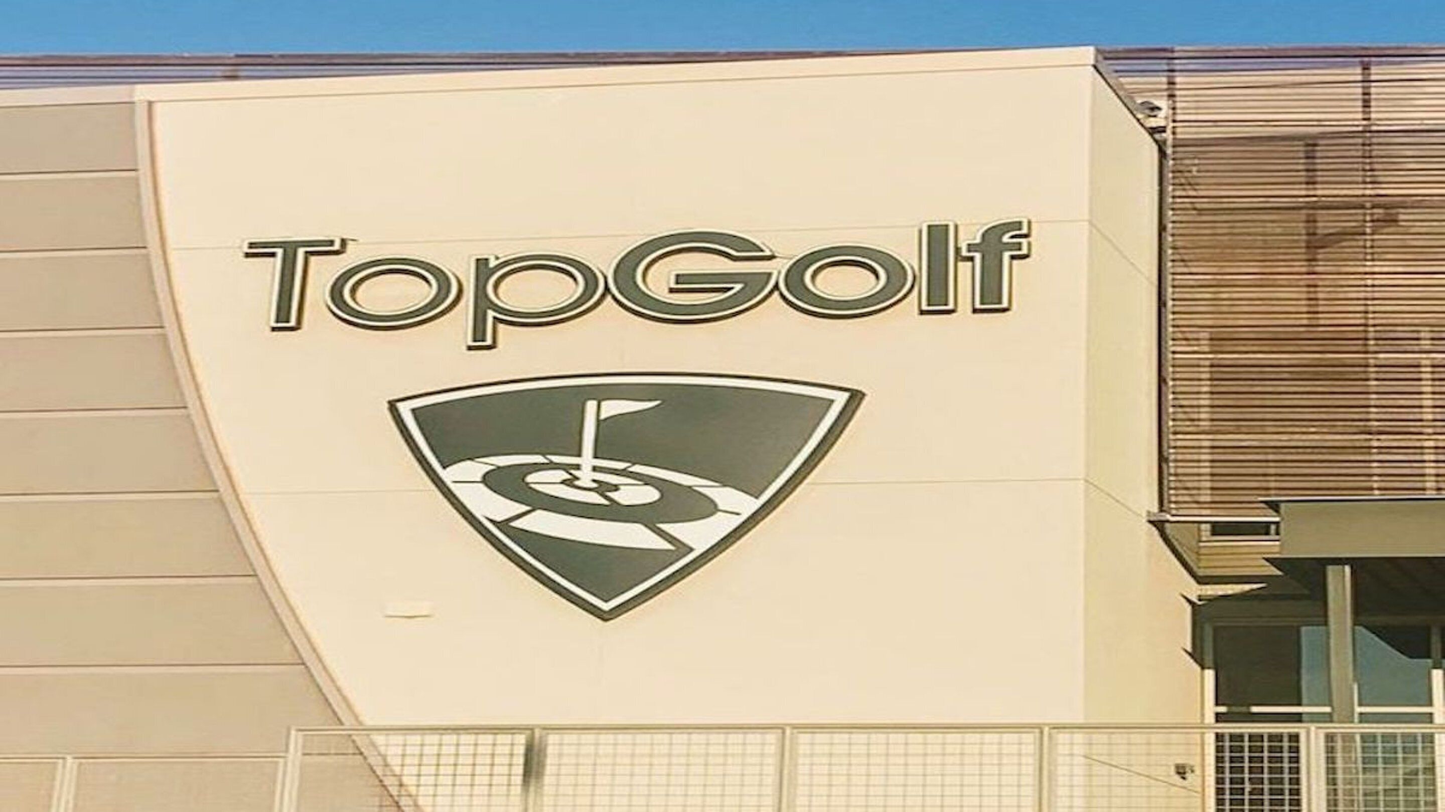 A building with a sign that reads "TopGolf" and a logo featuring a golf flag.