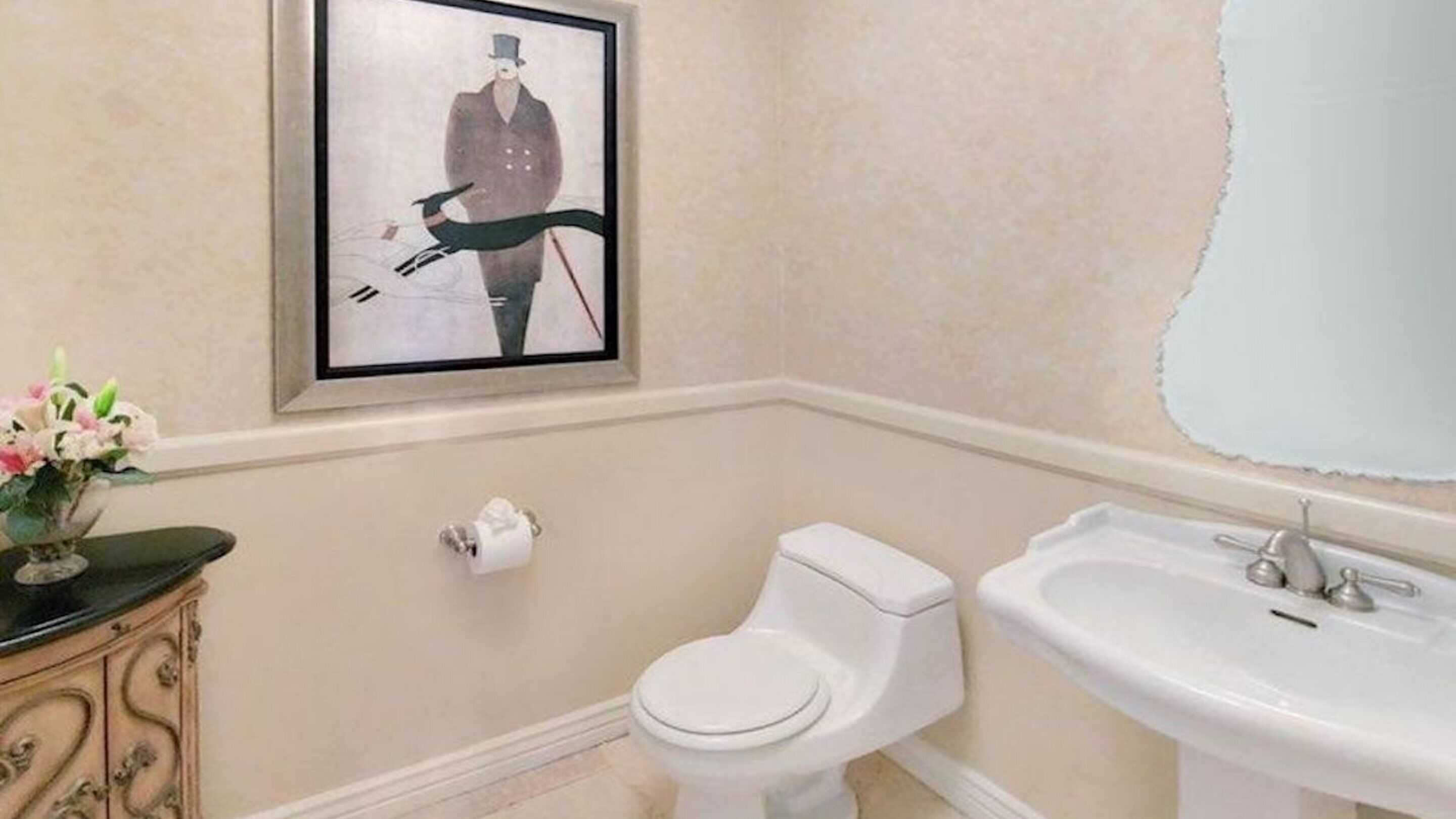Un baño con inodoro, lavamanos y un cuadro en la pared.