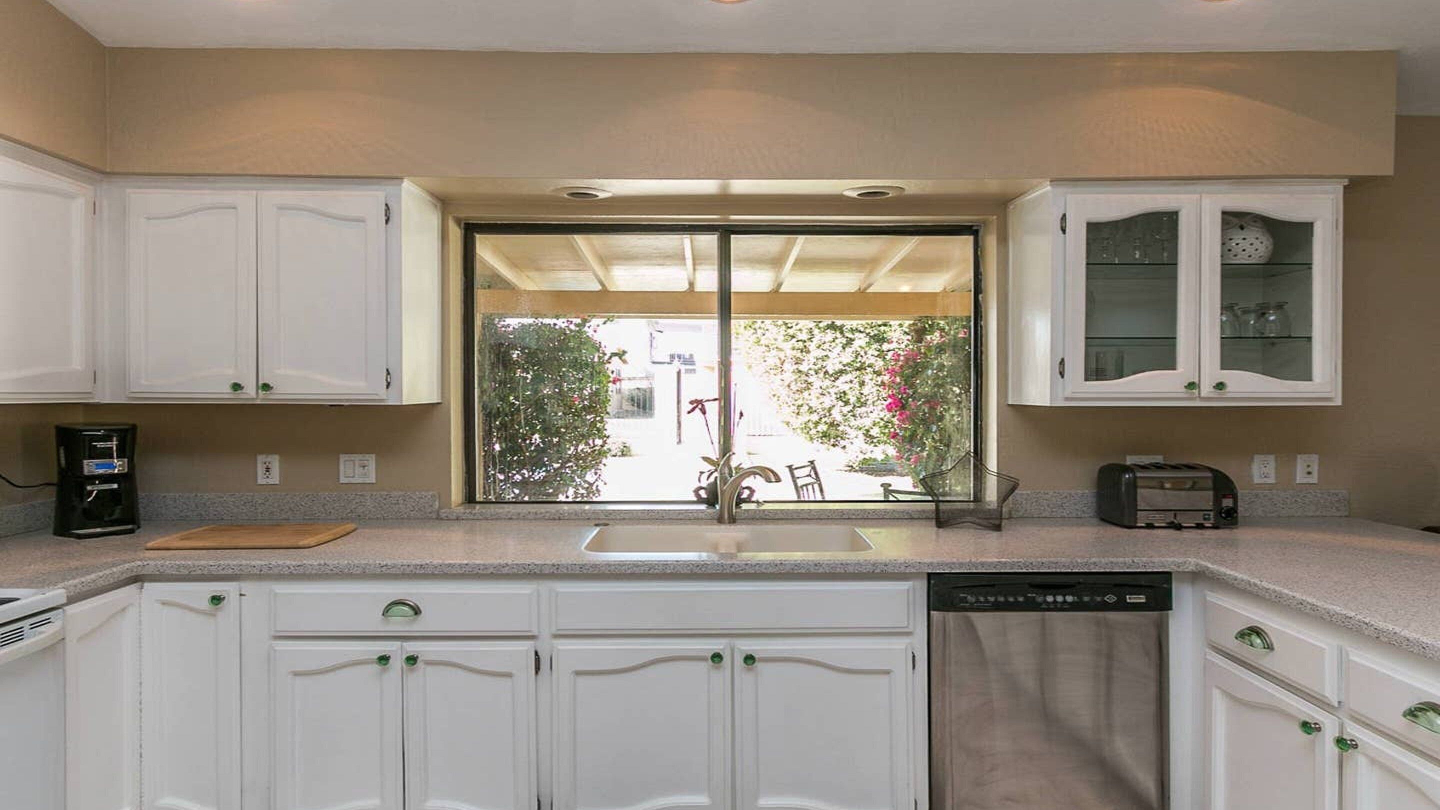 A kitchen with white cabinets, a coffee maker, a toaster, and a dishwasher.