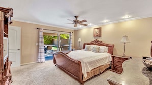 A bedroom with a large bed, a ceiling fan, a nightstand, a lamp, and a view of the outdoors through a sliding door. - Just Listed! Kierland Home w Htd Pool and Hot tub (Scottsdale)