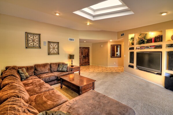 A living room with a sectional sofa, a coffee table, a flat-screen TV, and a fireplace.