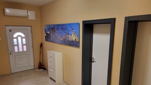 A hallway with a white door, a painting of a cityscape, a white cabinet, and a black door. - Apartment with terrace and barbecue (Vrsi)