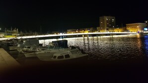 A nighttime marina with boats docked, a bridge in the background, and buildings along the waterfront. - Apartment with terrace and barbecue (Vrsi)