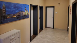 A hallway with beige walls, a painting of a cityscape, and a white cabinet. - Apartment with terrace and barbecue (Vrsi)