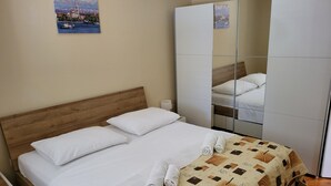 A neatly made bed with white linens and a patterned duvet, a wooden headboard, a bedside table with a lamp, and a large mirror reflecting the room. - Apartment with terrace and barbecue (Vrsi)
