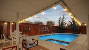 Un jardin avec une piscine, une terrasse en bois et du mobilier d’extérieur.