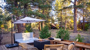 A wooden deck with a hot tub, wicker chairs, and a table with cushions. - Impeccable Mountain-Modern Home | Custom-Built Beds | Tesla Charger in Garage (Truckee)