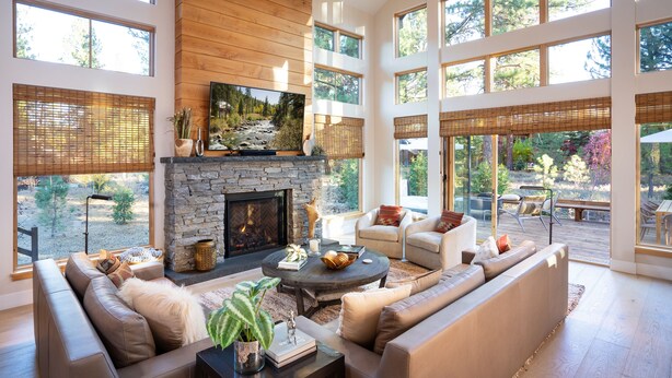 A spacious living room with a stone fireplace, large windows, and comfortable seating. - Impeccable Mountain-Modern Home | Custom-Built Beds | Tesla Charger in Garage (Truckee)