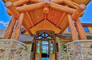 A log cabin with a stone foundation, a wooden porch, and a large entrance door.