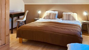 A bedroom with a large bed, two bedside lamps, a desk, and a chair.