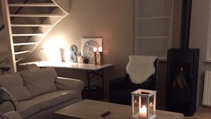A cozy living room with a sofa, a coffee table, a fireplace, and a staircase.