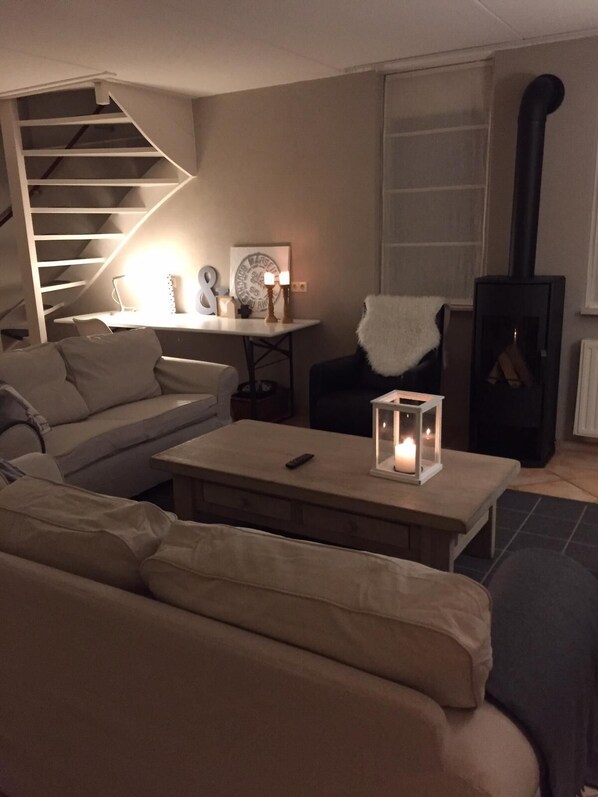 A cozy living room with a sofa, a coffee table, a fireplace, and a staircase.