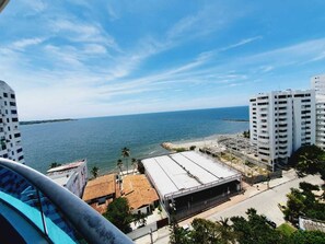 Vista costeira com praia, área de estacionamento e edifícios altos.