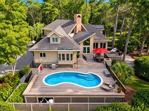 Una casa de dos pisos con piscina, terraza y mobiliario exterior.