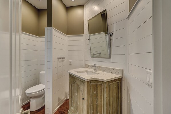 A bathroom with a toilet, sink, and mirror.