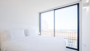 A bedroom with a large window, a bed, and a view of buildings.