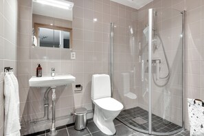 A modern bathroom with a glass-enclosed shower, a white sink, and a toilet.