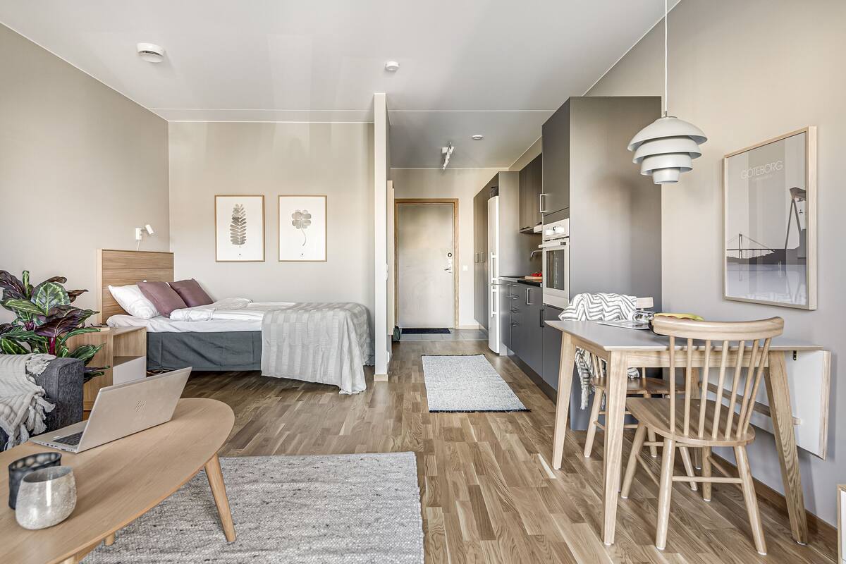A modern apartment with a bed, desk, and dining area.