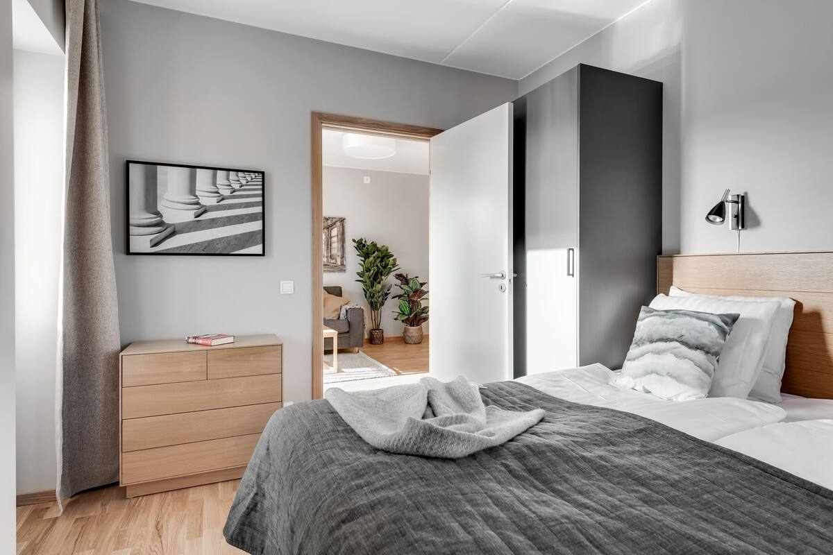 A modern bedroom with a bed, a dresser, and a framed picture on the wall.