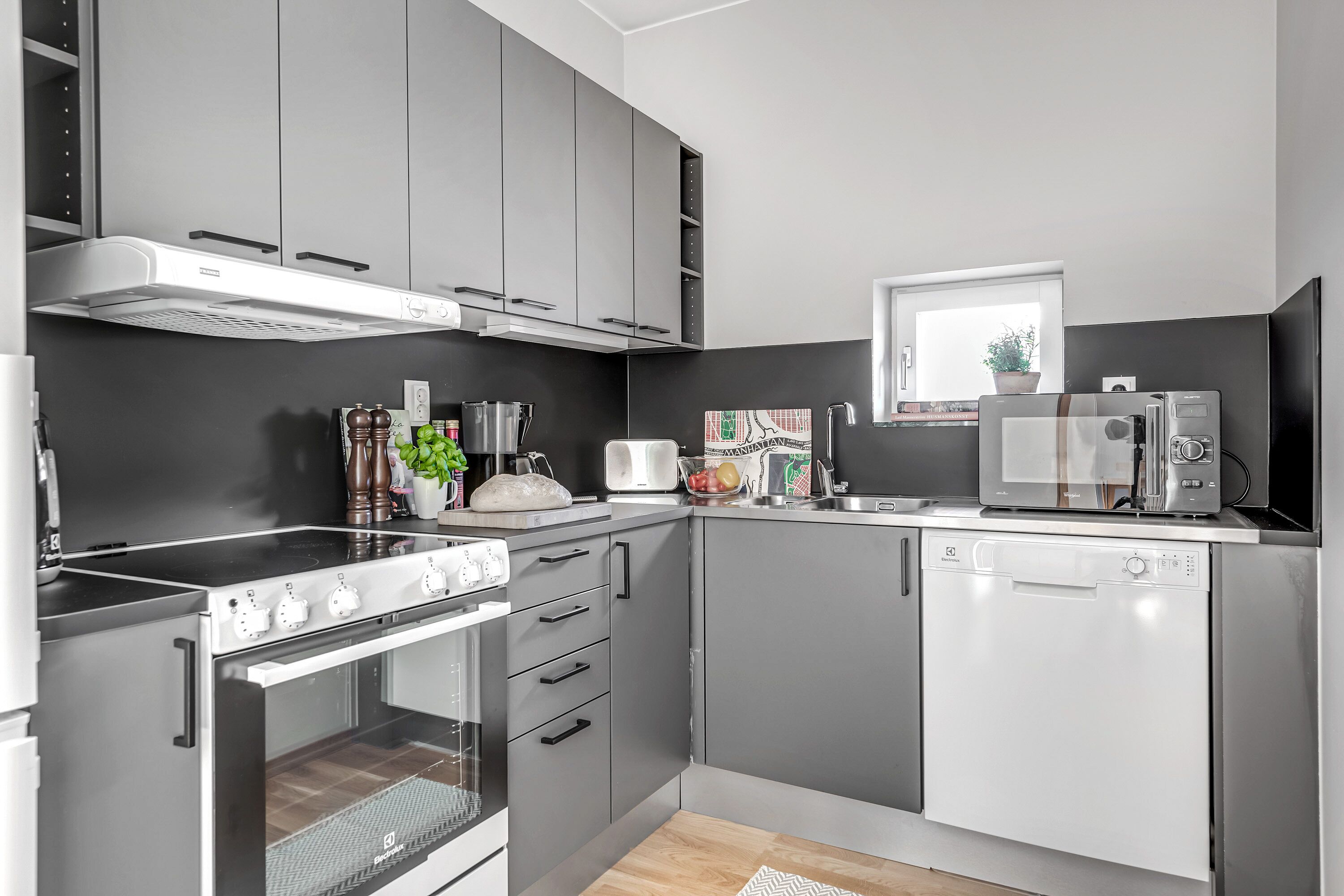 A modern kitchen with grey cabinets, a built-in oven, a dishwasher, and a microwave.