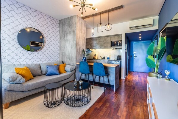 A modern living room with a grey sofa, blue chairs, and a small coffee table.