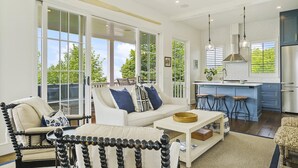 A spacious living area with a white sofa, a coffee table, and a dining area with stools. - New Downtown Petoskey Custom Home.  (Petoskey)
