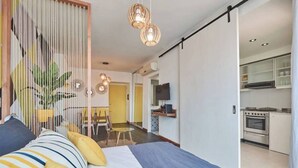 Una habitación de hotel moderna con cama, comedor y cocina.