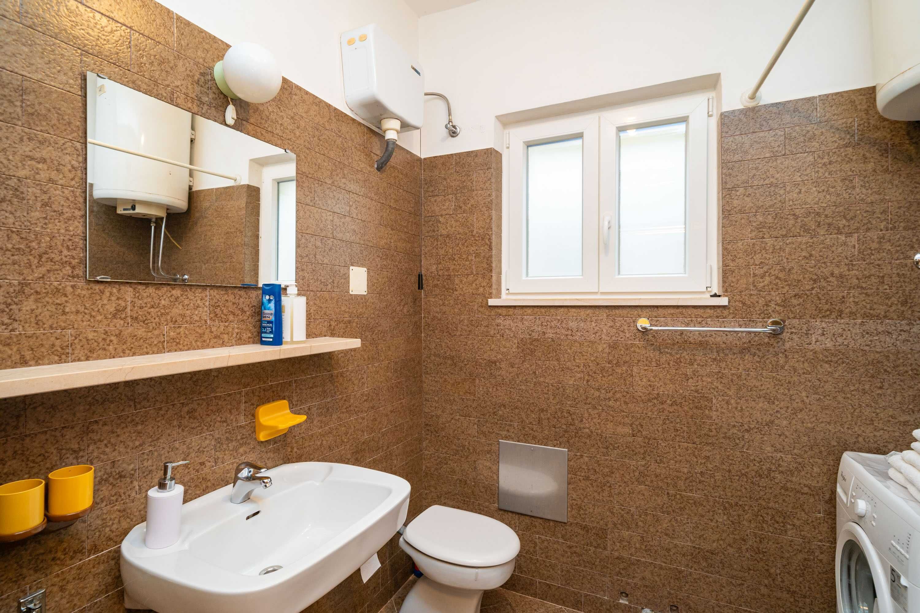 A bathroom with a sink, toilet, and a window.