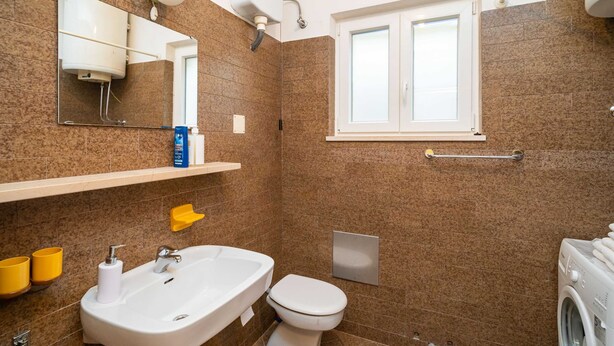 A bathroom with a sink, toilet, and a window.
