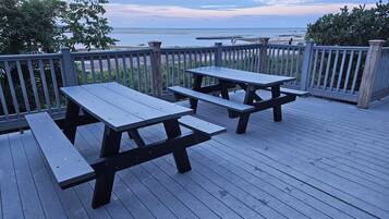 Une terrasse en bois avec des tables de pique-nique donnant sur une plage.